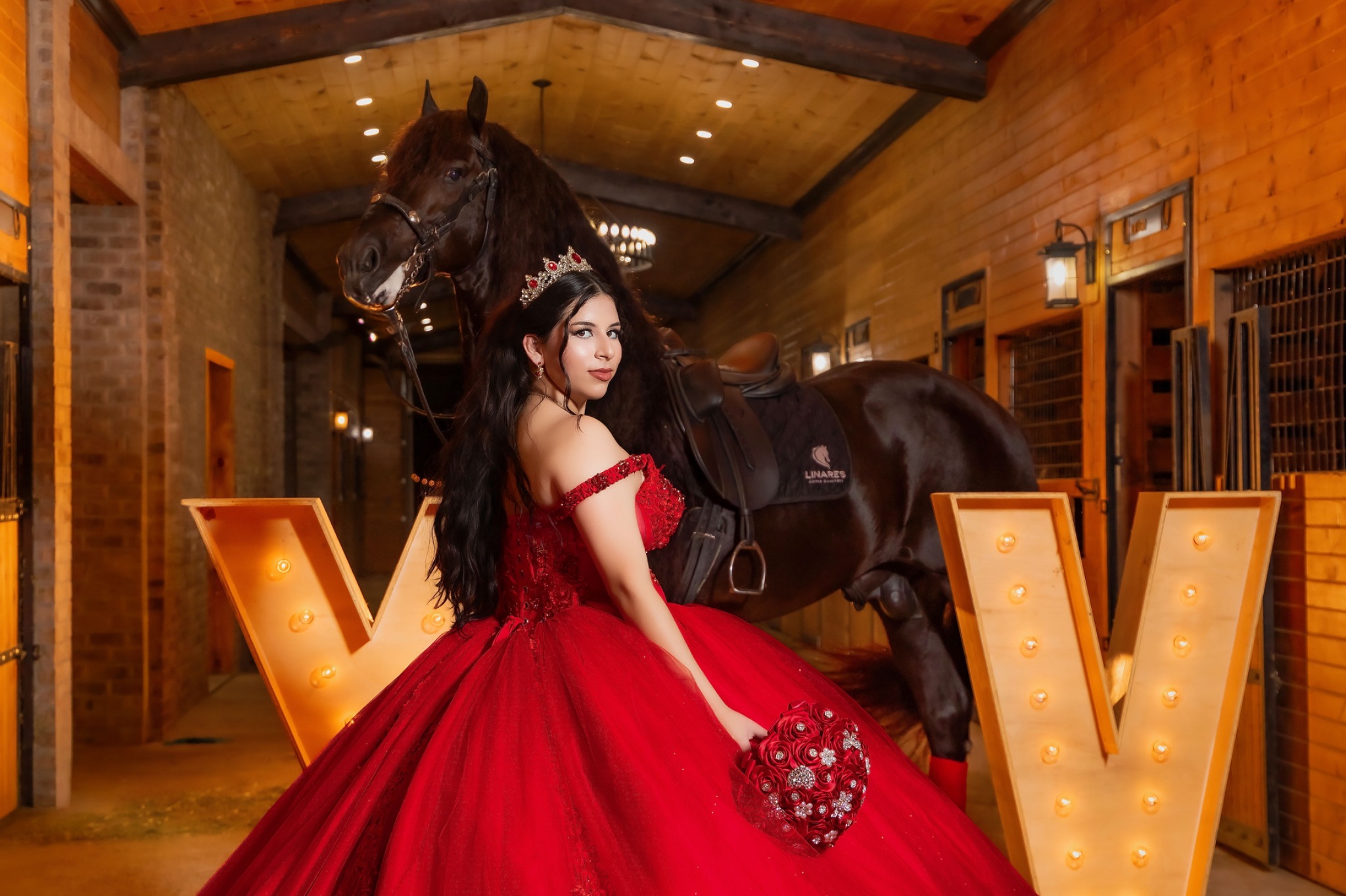 Quinceañera in a red gown posing with a horse